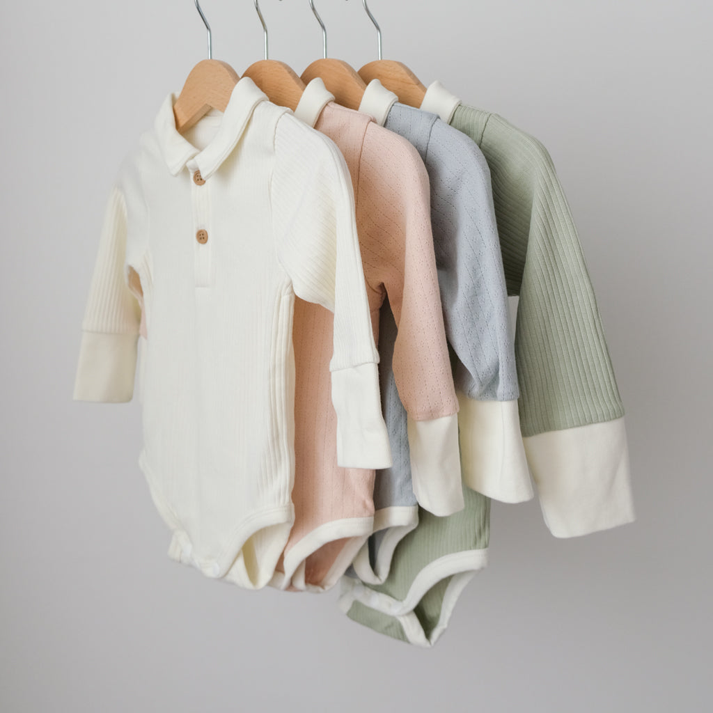 Our button bodysuits in all four colours: vanilla, peach, butterfly pea, and matcha.