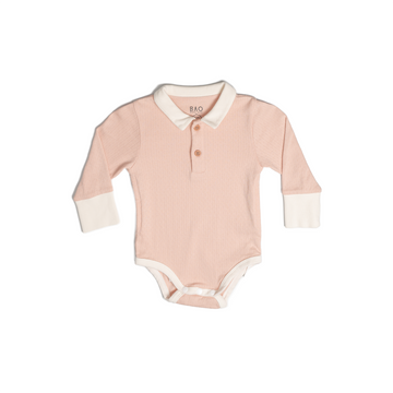 A long sleeve bodysuit, complete with a 2 buttons on the collar. In a gentle salmon pink (peach) pointelle patterned cotton. Shown in its large setting.