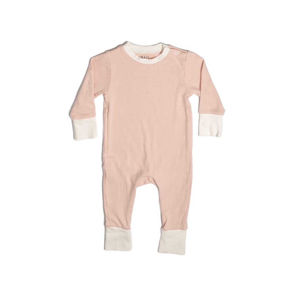 Pyjamas in a gentle salmon pink (peach), with vanilla colour contrasting wrist and ankle cuffs. Made from pointelle patterned cotton. Shown in its large setting.