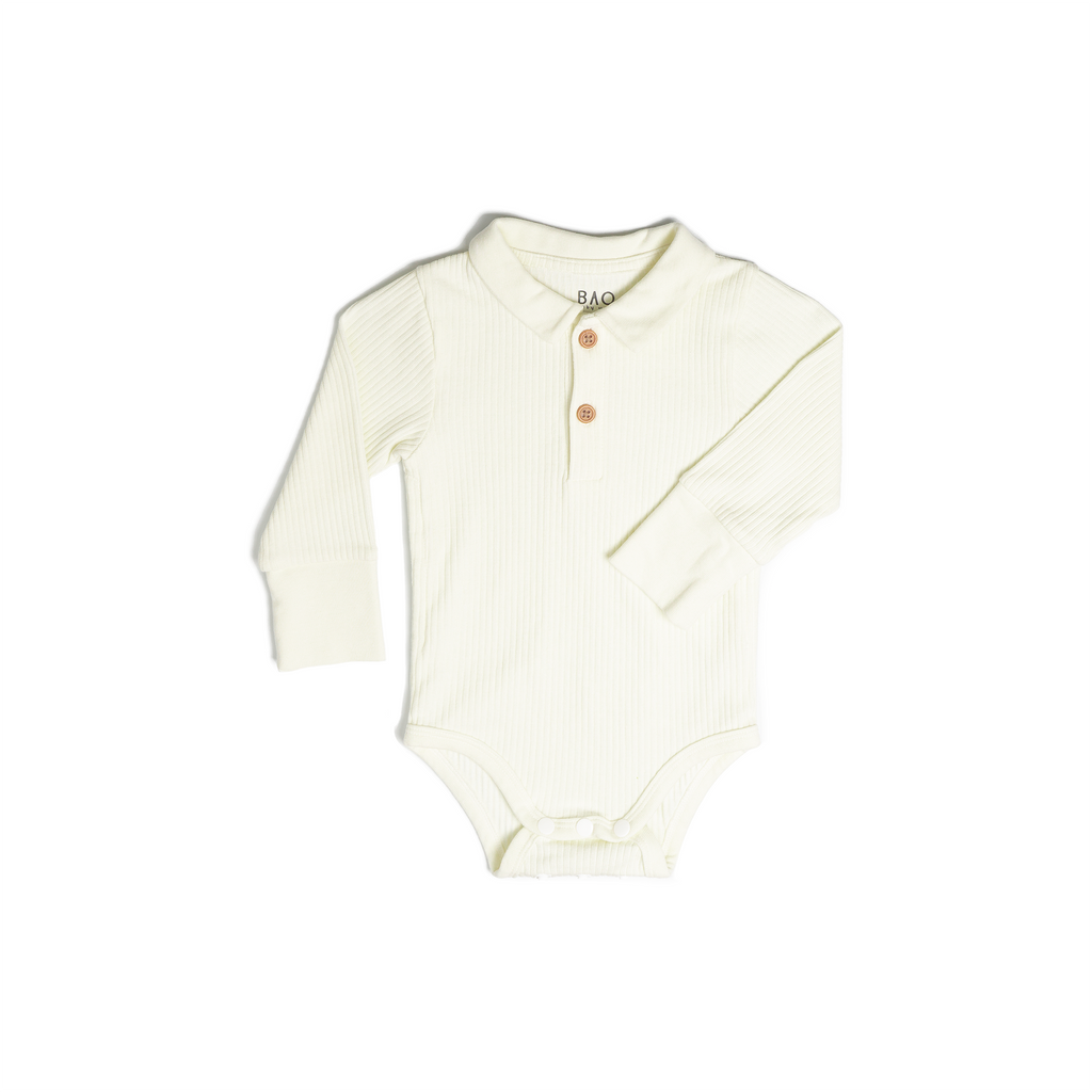 A long sleeve bodysuit, complete with a 2 buttons on the collar. In a slightly off white (vanilla) ribbed cotton. Shown in its large setting.