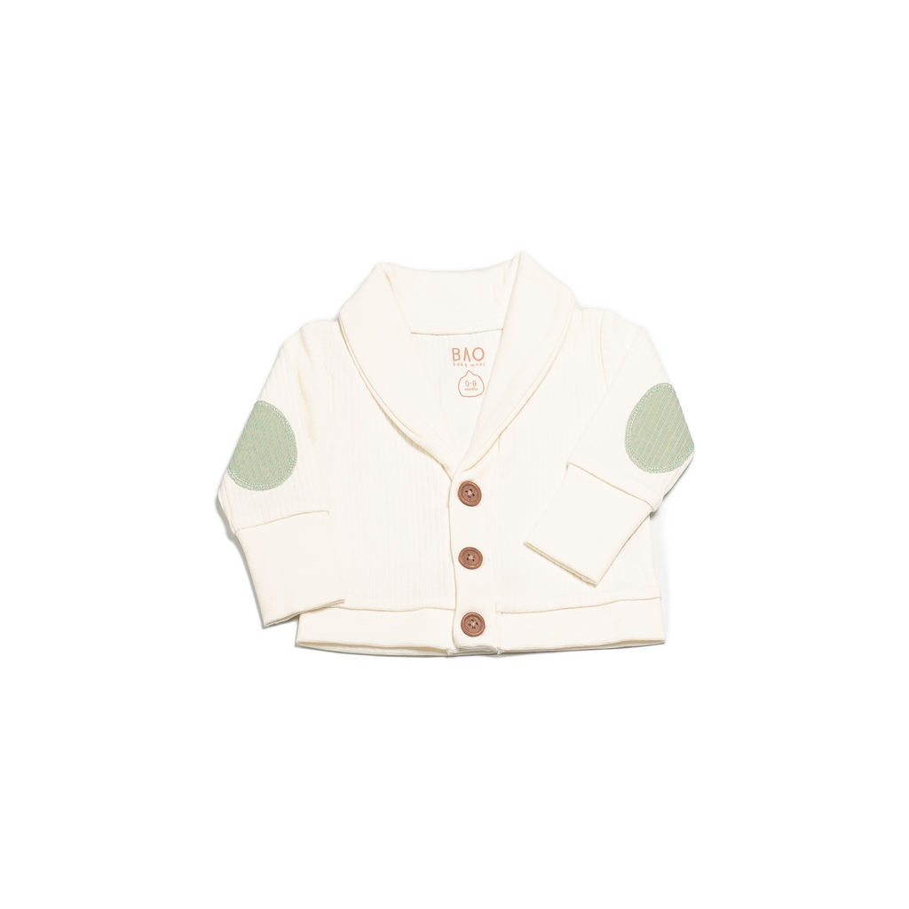 An off white (vanilla) cardigan featuring contrasting elbow patches in a matcha green, complete with 3 buttons. Made from a soft ribbed cotton. Shown in its large setting.
