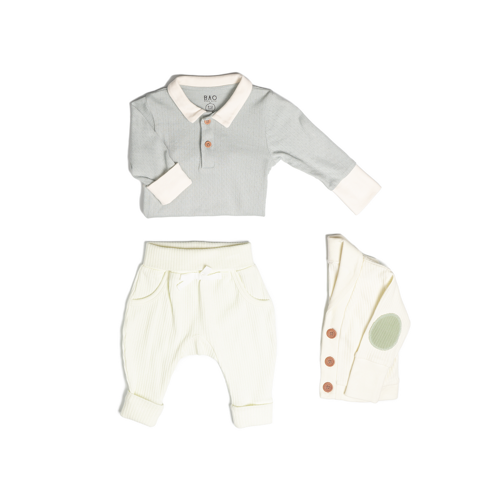 The toddler essentials bundle, consisting of a collared bodysuit in a gentle blue (butterfly pea) pointelle patterned cotton, paired with lounge pants in vanilla and ribbed cotton and a cardigan in vanilla ribbed cotton.