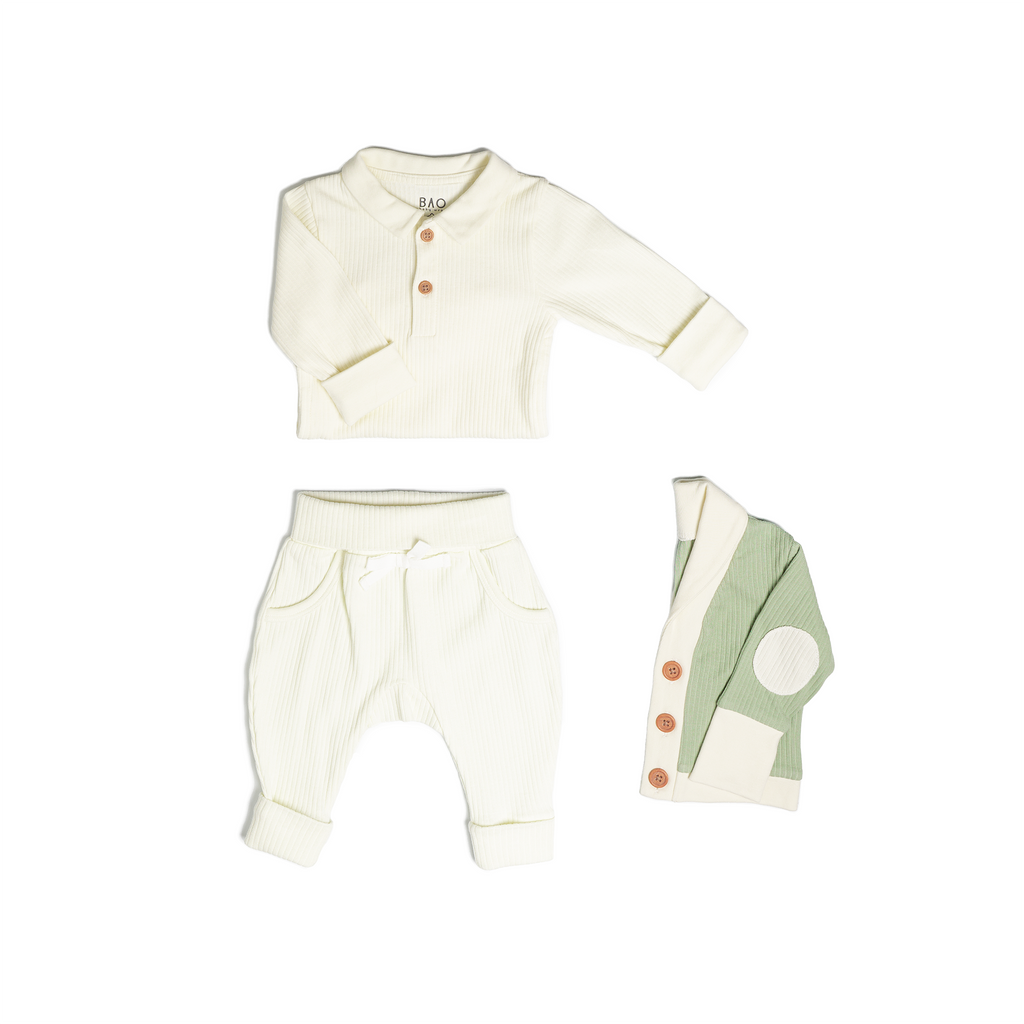 The toddler essentials bundle, consisting of a collared bodysuit in vanilla ribbed cotton, paired with lounge pants in vanilla and ribbed cotton and a cardigan in matcha ribbed cotton.