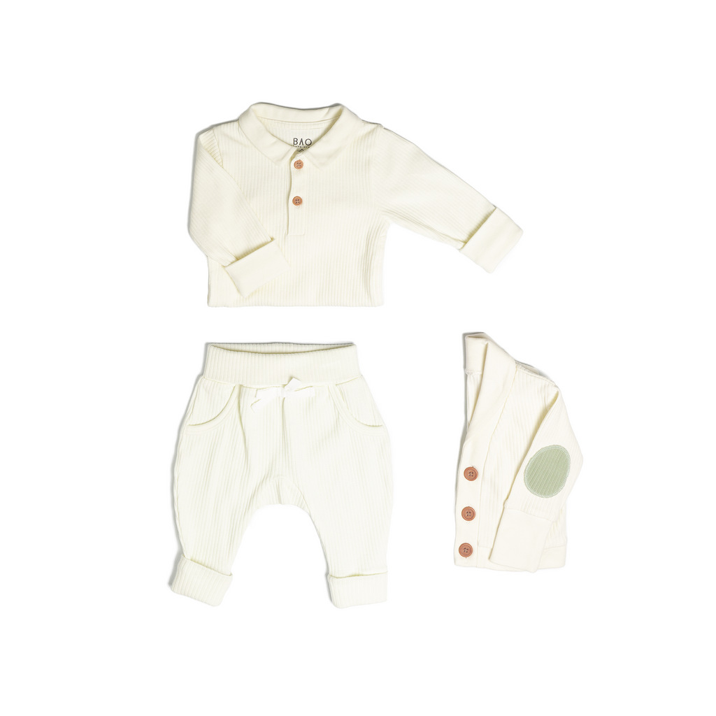 The toddler essentials bundle, consisting of a collared bodysuit in vanilla ribbed cotton, paired with lounge pants in vanilla and ribbed cotton and a cardigan in vanilla ribbed cotton.